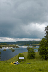 Easel and stool sit ready on the slope, waiting for inspiration of artist. Overcast sky looms above...
