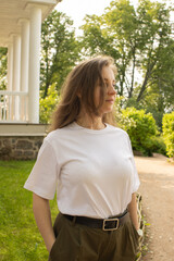 Female tourist in casual clothes enjoying the grounds of a heritage mansion. Beautiful light, classic fence, and serene garden path highlight the harmony between history and modern simplicity.