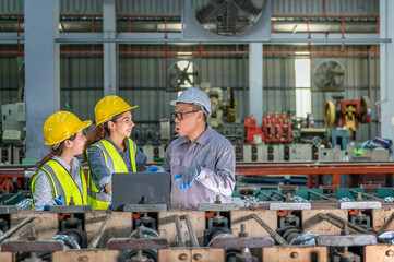 Group of industrial workers wea yellow safety helmets and reflective vests having a discussion with...