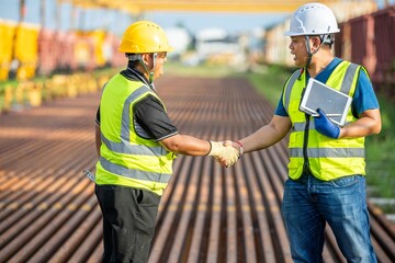 Two engineers shake hand in rail Industrial meeting cooperation, engineers team in Construction site handshake Workers for Deal Agreement Partnership in Engineering Field