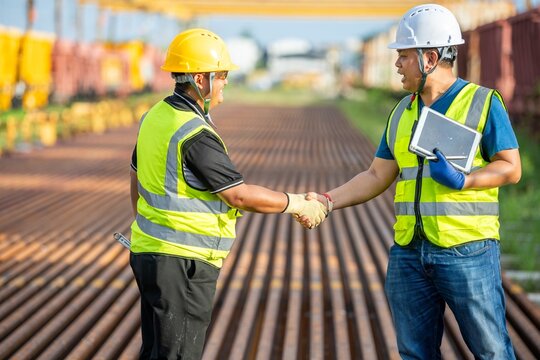 Two engineers shake hand in rail Industrial meeting cooperation, engineers team in Construction site handshake Workers for Deal Agreement Partnership in Engineering Field - Powered by Adobe