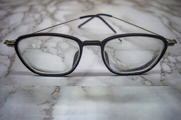 Black vintage eyeglasses with clear lenses resting on marble surface, showcasing elegant design, clarity, and timeless style. Ideal for fashion, vision, and lifestyle themes