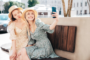 Two young beautiful smiling hipster female in trendy summer dress  clothes. Blond carefree women...