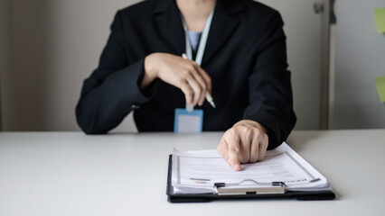 Businesswoman employer sitting holding new employee's documents to evaluate and review new employee's personal history. Recruitment concept, job placement