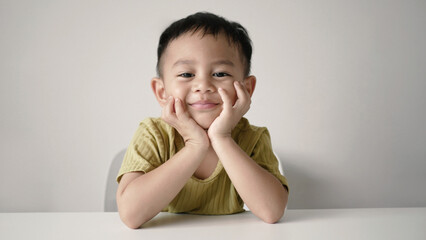 Little Asian boy sitting smiling sweetly on white background. Innocent girl
