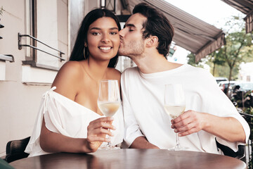 Smiling beautiful woman and her handsome boyfriend. Happy cheerful family. Sexy couple cheering with glasses of red wine at their date in restaurant. Drinking alcohol at veranda cafe