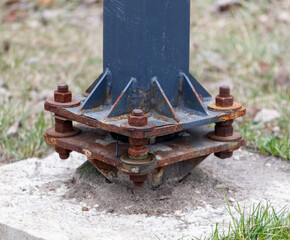 A rusted metal pole with bolts and nuts on it