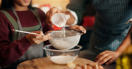 Baking, flour and hands of child with parent in kitchen of home for development, help or tradition. Kid, learning and sieve utensil with family in apartment together for cooking or how to bake