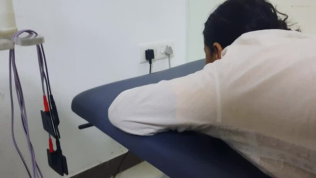 patient lying at plinth for physiotherapy session with electrode at indoor