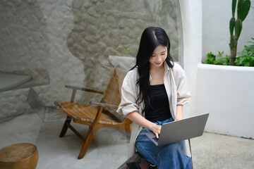 Freelancer woman focused on her laptop at a stylish caf with a natural, modern design.