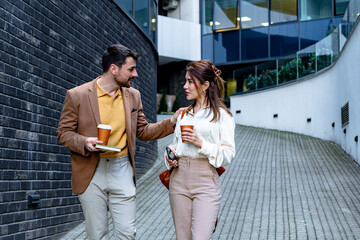 Businessman and businesswoman engaging in a lively discussion while walking outdoors, enjoying...