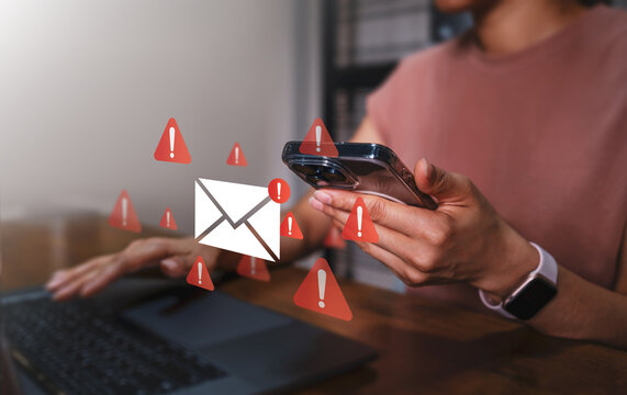 Company employee using laptop computer with warning email inbox icons, cybersecurity alert, spam risk concept