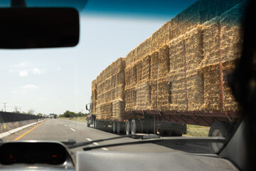 Truck carrying hay bales driving on highway on sunny day