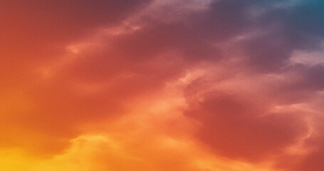 Obraz premium Abstract image of a sky with orange, red, and blue tones blending together. Suggests a vivid sunset or twilight with soft cloud formations.