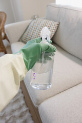 Cleaning a couch with spray bottle and gloves