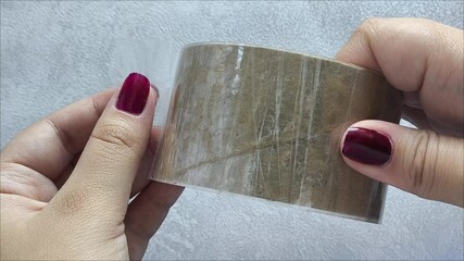 girl holding a roll of tape in hand. The woman unwinds the tape. - Powered by Adobe