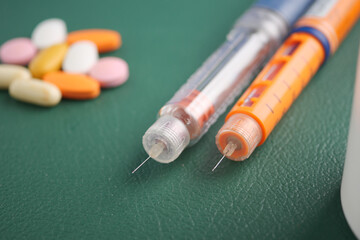 Medications and insulin on a green surface