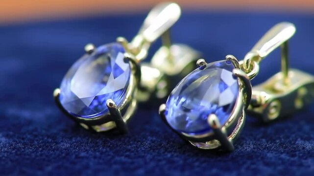 Gold cufflinks with blue gemstones on a blue velvet background
