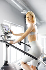 Young woman in sportswear working out at the gym. She is working out on stairway simulator