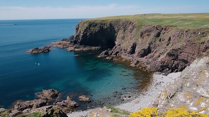 A secluded cove with crystal-clear turquoise waters nestled between dramatic red cliffs and a grassy headland, under a vibrant blue sky