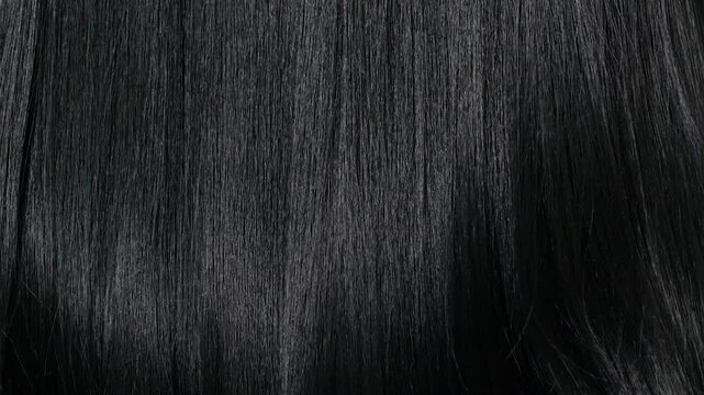 Closeup human long hair texture in slow motion, black straight hair background