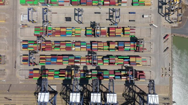 Aerial drone shot Felixstowe busy port cargo ships, shipping containers, huge cranes, loading and unloading heavy goods vehicles summer maritime business England UK