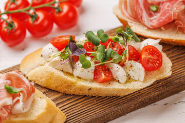 Tasty antipasto toasts featuring classic caprese with mozzarella and tomatoes, and savory prosciutto with herbs