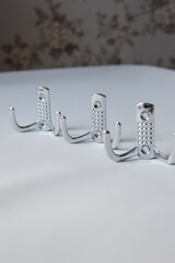 set of three metal wall hooks aligned on white background, ideal for concepts of home storage,...