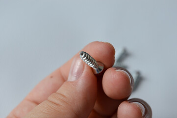 close-up of a person holding a small metal screw, concept of home improvement, hardware details,...