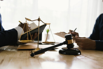 Close-up of lawyer giving legal advice showing gavel, scales and expert examining documents,...
