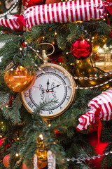 The clock hands on the dial show 12 o'clock. Golden retro clock on a Christmas tree. Beautiful...