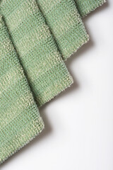 An abstract photograph of folded green plastic mesh with diagonal lines casting shadows on a gray background