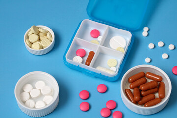 Daily pill organizer box with various pills and capsules displaying different colors and shapes on...