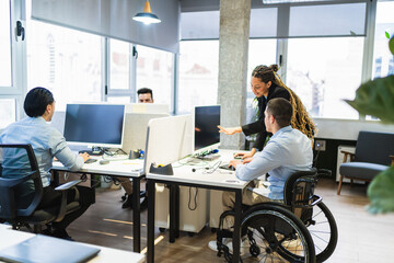 Coworkers and manager collaborating in a modern office, focusing on accessibility and inclusion in...