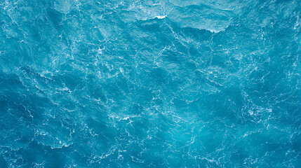 Aerial view of vibrant blue ocean water with visible waves and white foam patterns across the surface.