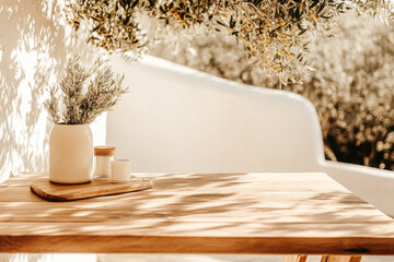 Sunlit table with olive branches and ceramic vessels in outdoor rustic setting