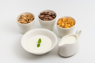 Assorted cereals with yogurt and milk on rustic wooden table