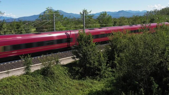 The train moves fast across vast green trees and bushes, captured in a spectacular aerial view.