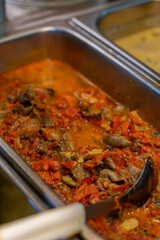 Spicy Indonesian dish of chicken liver and gizzard cooked in chili sauce, served in a stainless tray at a food stall or buffet.