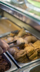 Traditional Indonesian dishes of boiled eggs and fried tofu served in a food stall warmer. Authentic street food in a local warung eatery.