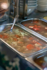 Authentic Indonesian clear broth soup featuring tender beef, carrots, cauliflower, and peas, served...