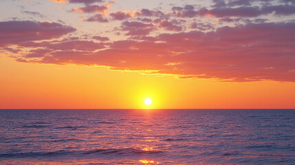 A vibrant sunset over a calm ocean with scattered clouds and a glowing horizon.