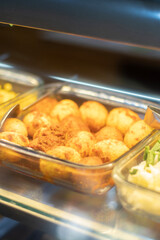 Traditional Indonesian boiled eggs in spicy chili sauce, known as telur balado, served in a glass food warmer in a local restaurant or food stall.