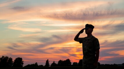 Silhouette of a soldier saluting against an expressive sunset background