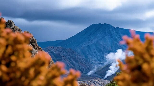 Stunning views of Mount Bromo, in Indonesia, with clouds of smoke rising, framed by foliage, highlighting the majestic peak and volcanic activity.