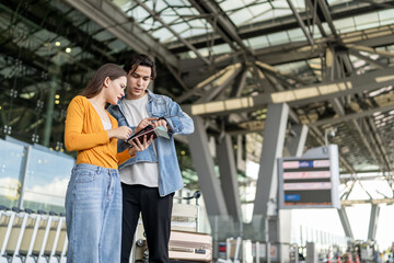Fototapeta premium Asian young couple passenger looking lost outside the airport terminal. 