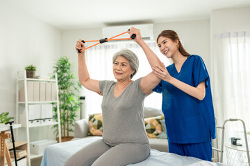 Elderly Asian woman receive physical therapy with support of caregiver. 