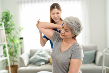 Elderly Asian woman receive physical therapy with support of caregiver. 