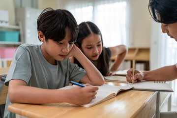 Asian students learning with teacher in classroom at elementary school.