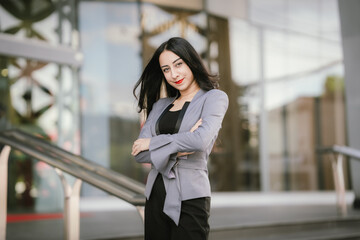 Fototapeta premium A confident woman in a gray blazer stands tall in an urban setting, showcasing elegance, strength, and ambition through her professional style, beauty, and empowered presence.
